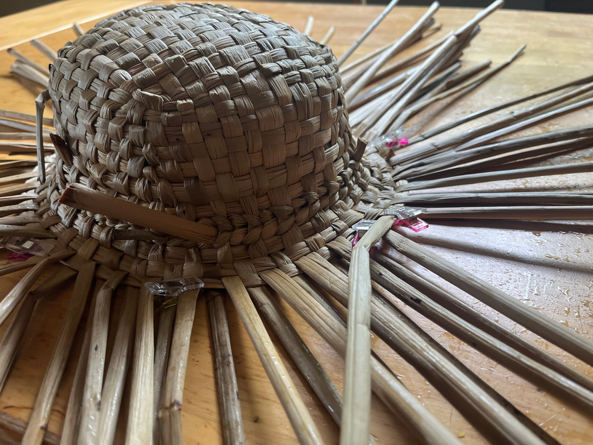 Finished hand-woven rush hat held in hand